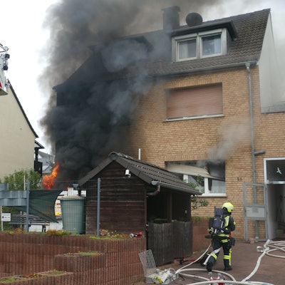 Eine Rauchsäule steigt vor einem Haus auf.