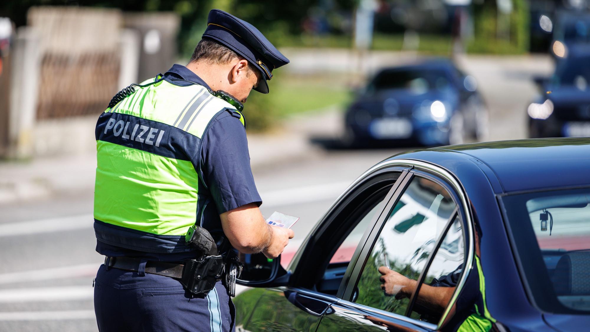 05.09.2024, Bayern, Burghausen: Eine Polizist der Bayerischen Grenzpolizei kontrolliert an einer Kontrollstelle die Dokumente eines Autofahrers.