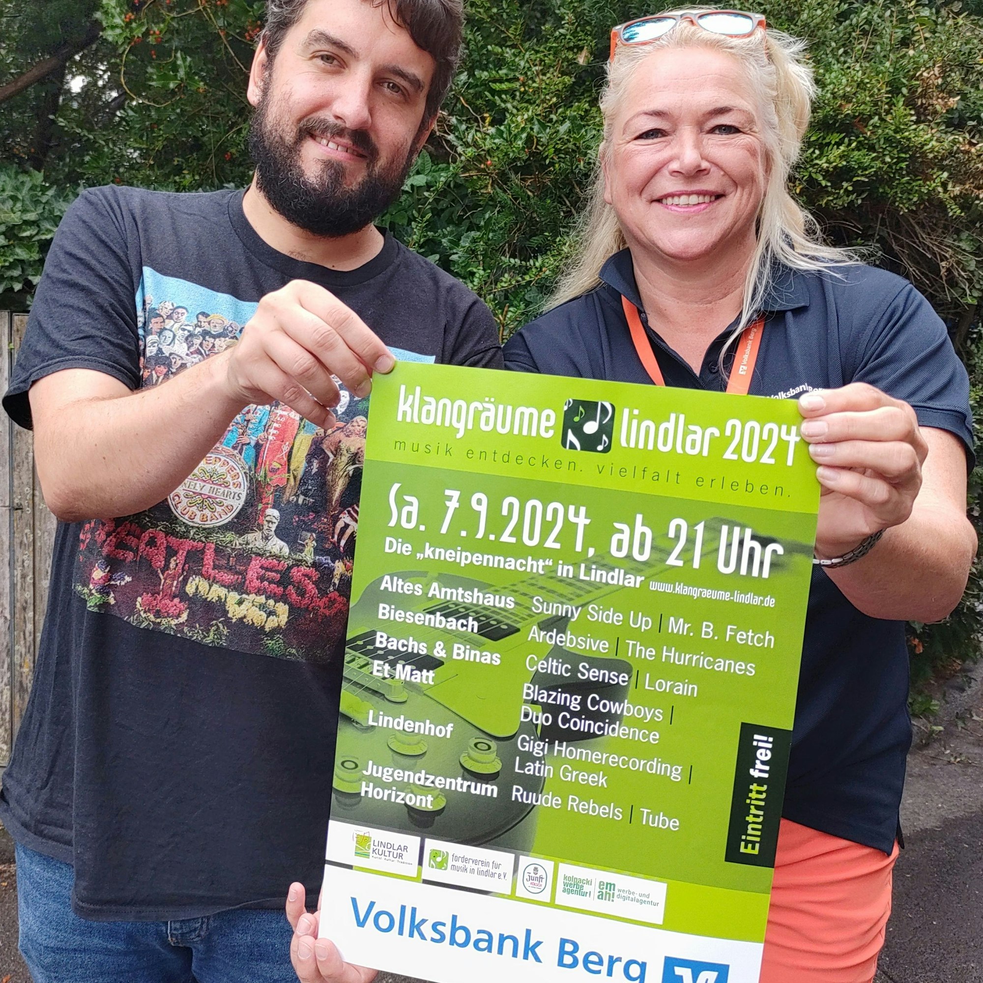 Niklas Pinner und Tanja Paas halten ein Plakat der Klangräume Lindlar in die Kamera. Die 13. Lindlarer Knaipennacht findet am 7. September statt.