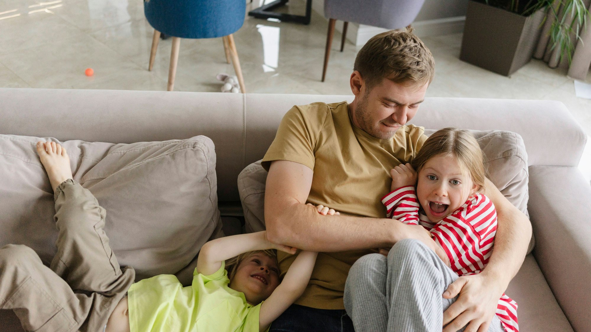 Vater spielt mit zwei Kindern auf der Couch