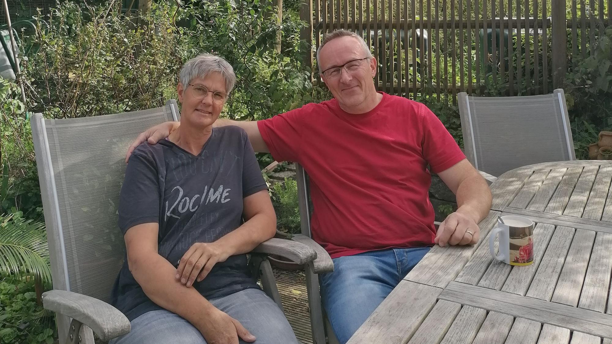 Claudia und ihr Ehemann sitzen in ihrem Garten.