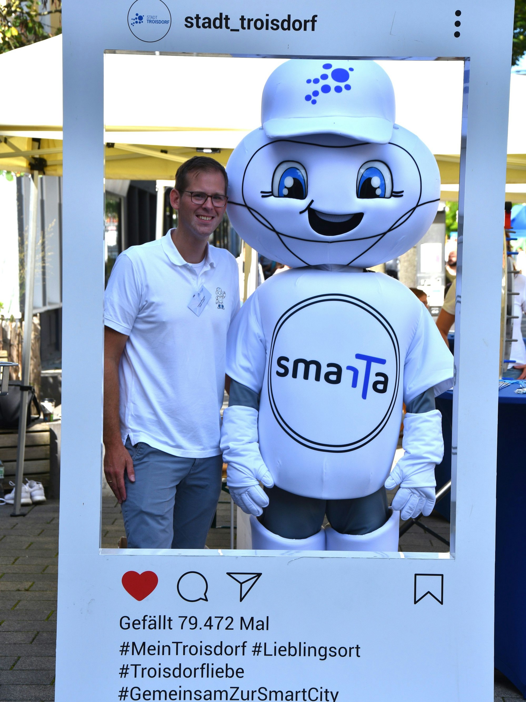 Ein Mann steht neben einem Maskottchen in einem Bilderrahmen.