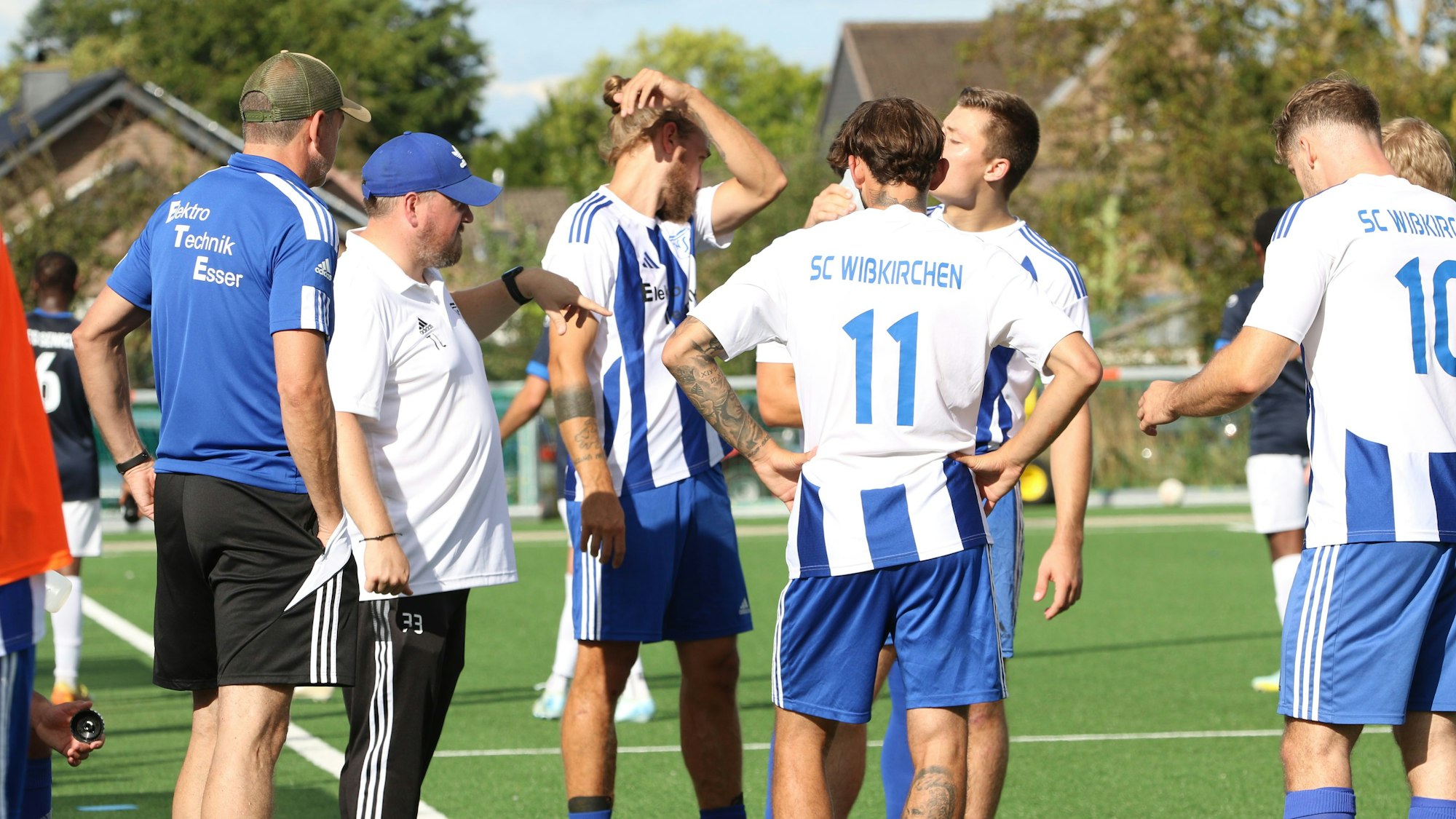 Der Co-Trainer und mehrere Spieler stehen in einer Gruppe zusammen.