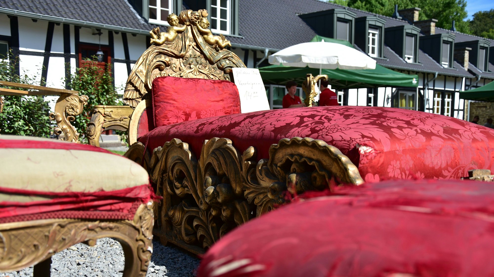 Alte Polstermöbel mit zerschlissenem Stoff stehen auf dem Hof einer Fachwerkanlage.