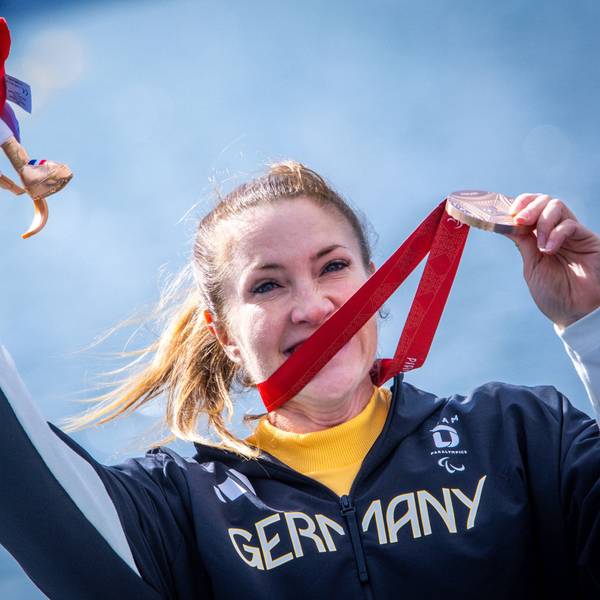 Edina Müller jubelt nach dem Rennen mit ihrer Bronzemedaille und hält Phryges, das Maskottchen der Paralympics, in ihrer Hand.