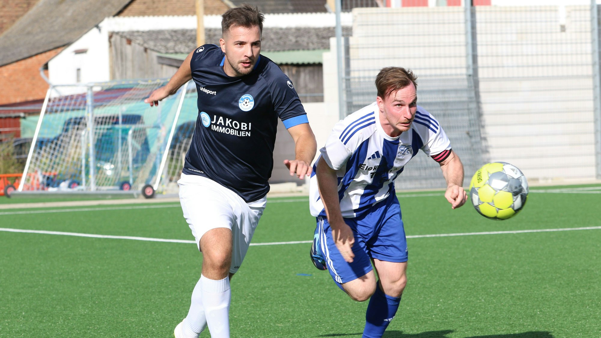 Die beiden Spieler laufen nebeneinander, beide wollen den Ball als Erster erreichen.