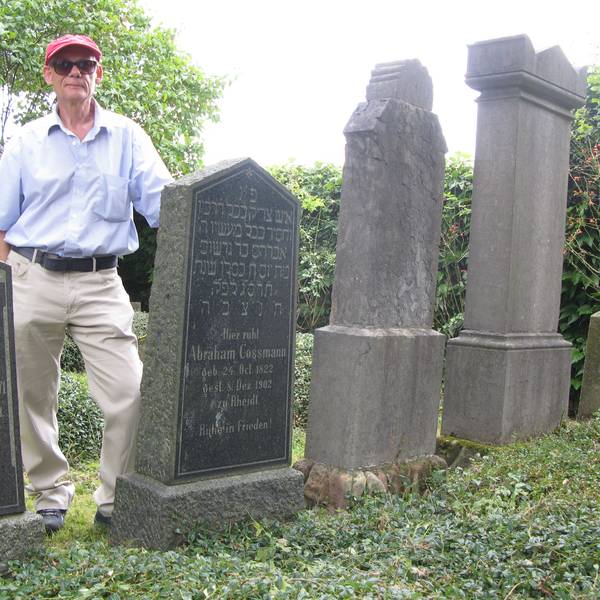 Ein Mann steht zwischen zwei Grabsteinen auf einem alten jüdischen Friedhof.