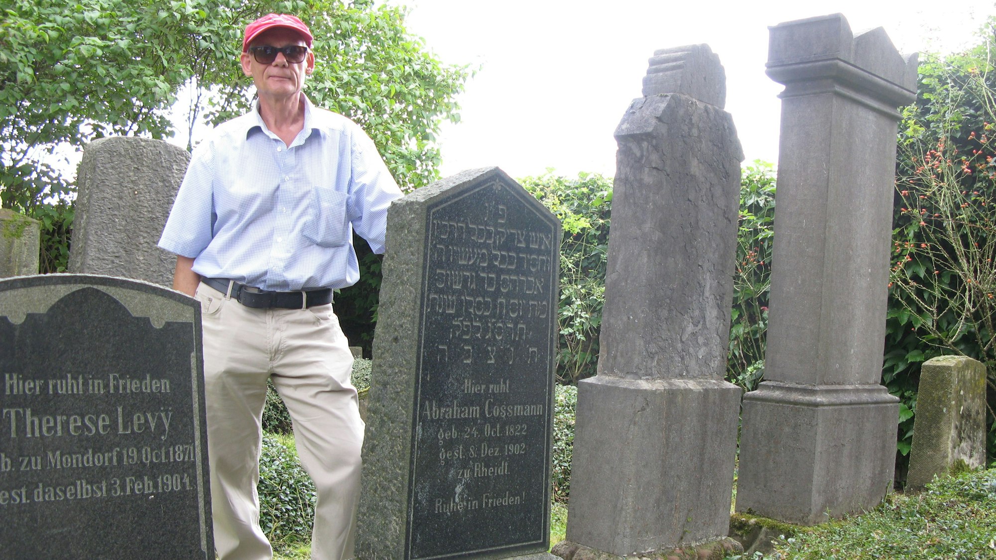 Ein Mann steht zwischen zwei Grabsteinen auf einem alten jüdischen Friedhof.
