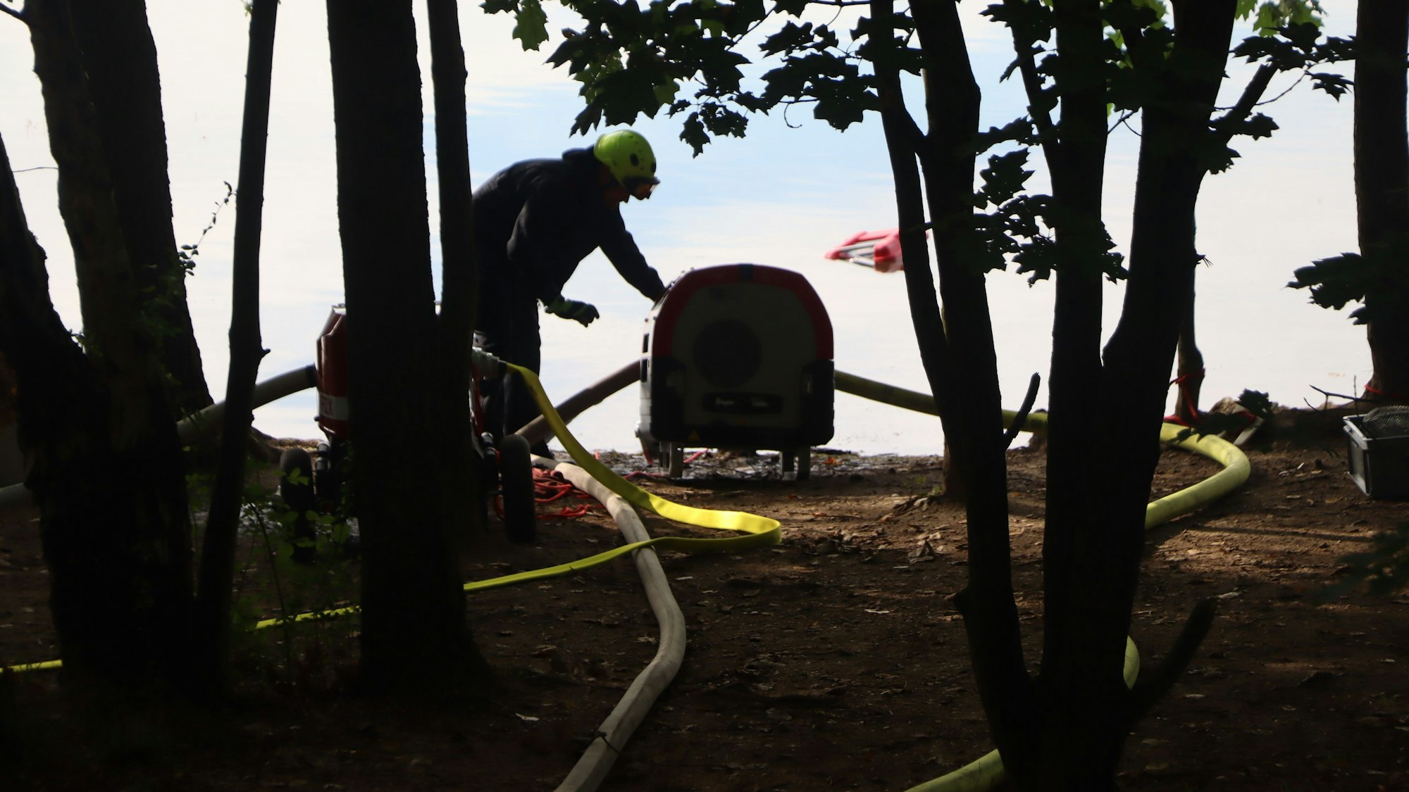 Ein Feuerwerhmann pumpt Wasser aus einem See.