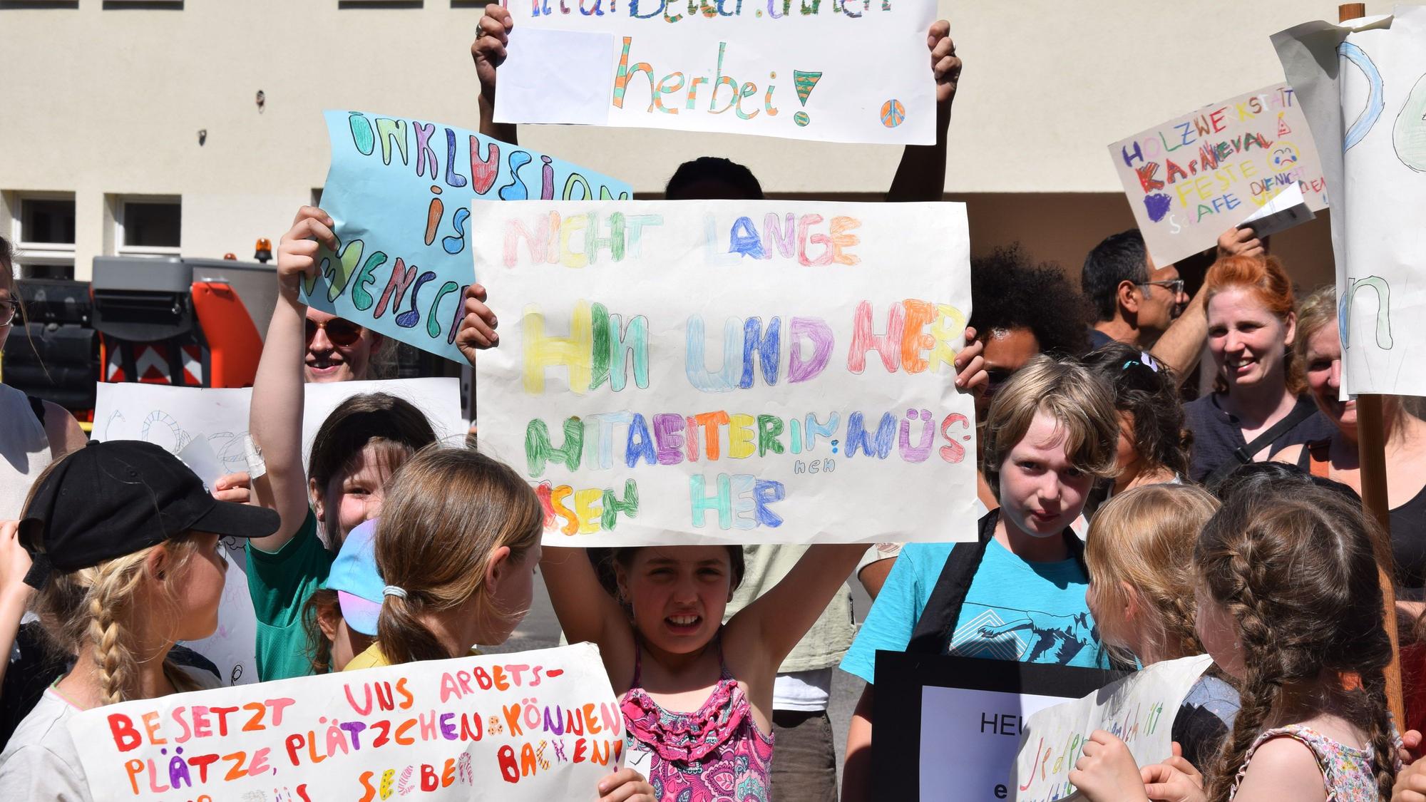 Kinder halten bunte Protestplakate hoch.