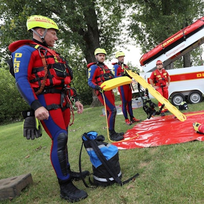 Männer in Neoprenanzügen und gelben Helmen.