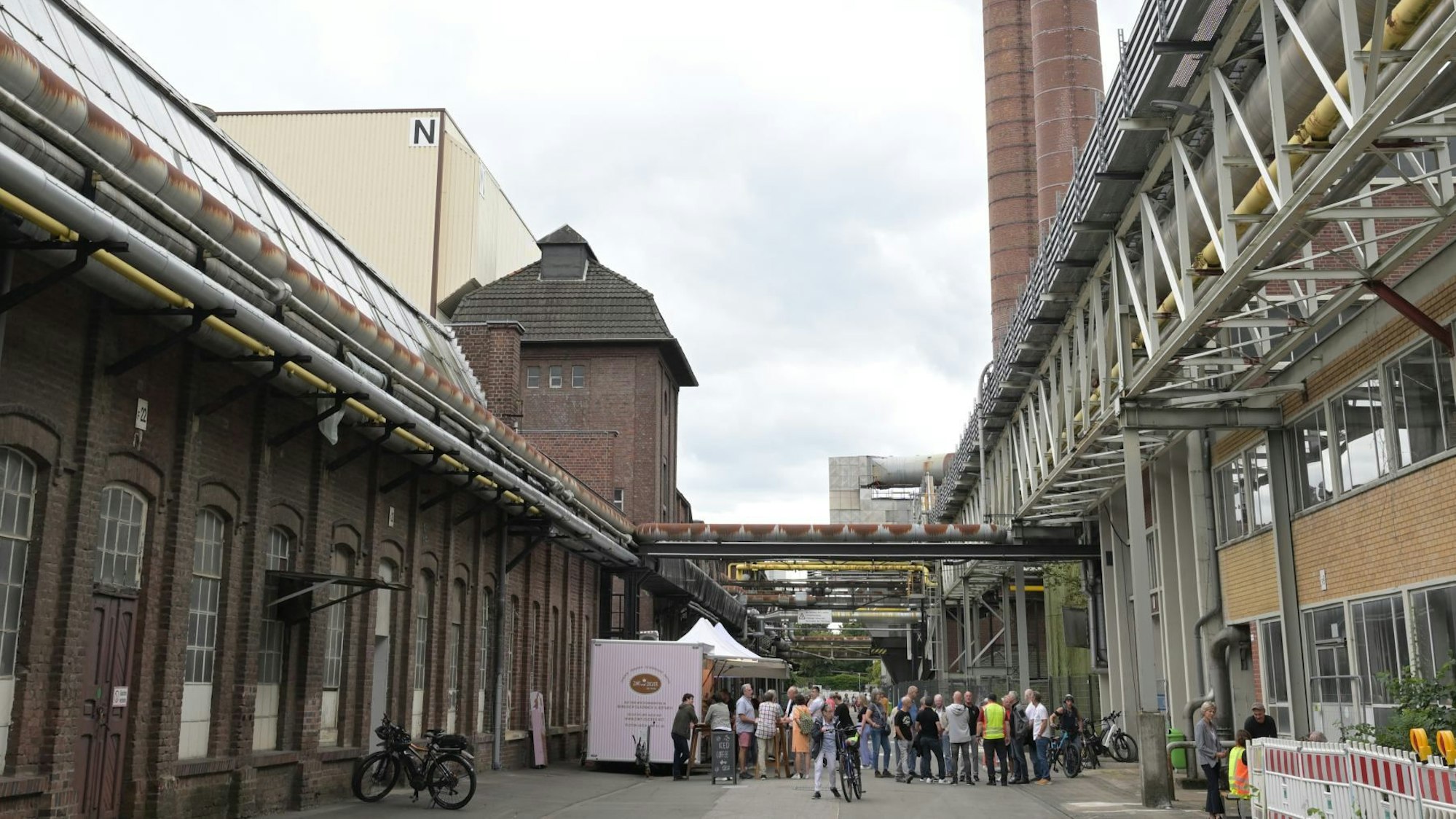 Menschen stehen auf der Mainstreet des Zanders-Geländes an eine Kaffeebude.