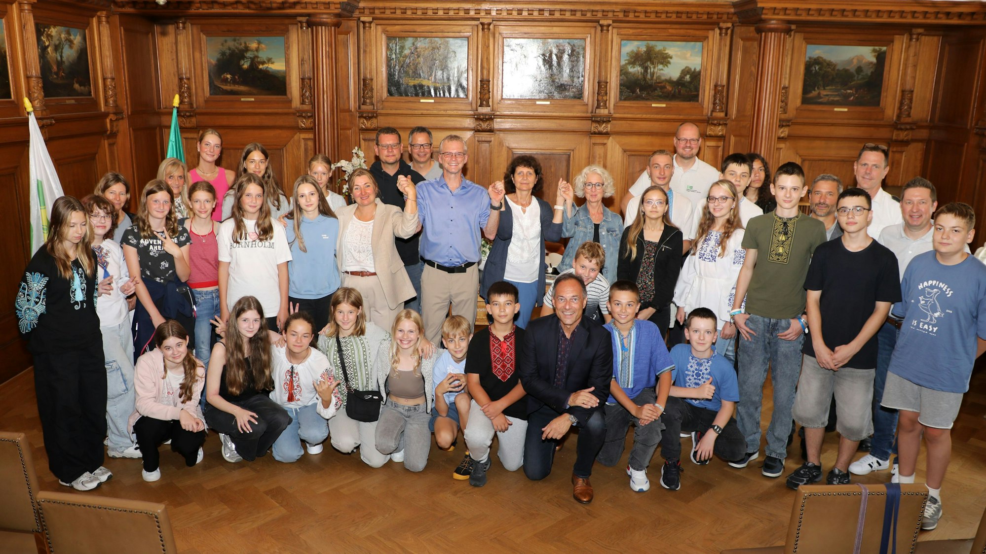 Im Rathaus steht Bürgermeister Frank Stein mit Schüler aus Butscha und ihren Gastgebern von der Integrierten Gesamtschule Paffrath im großen Ratssaal.