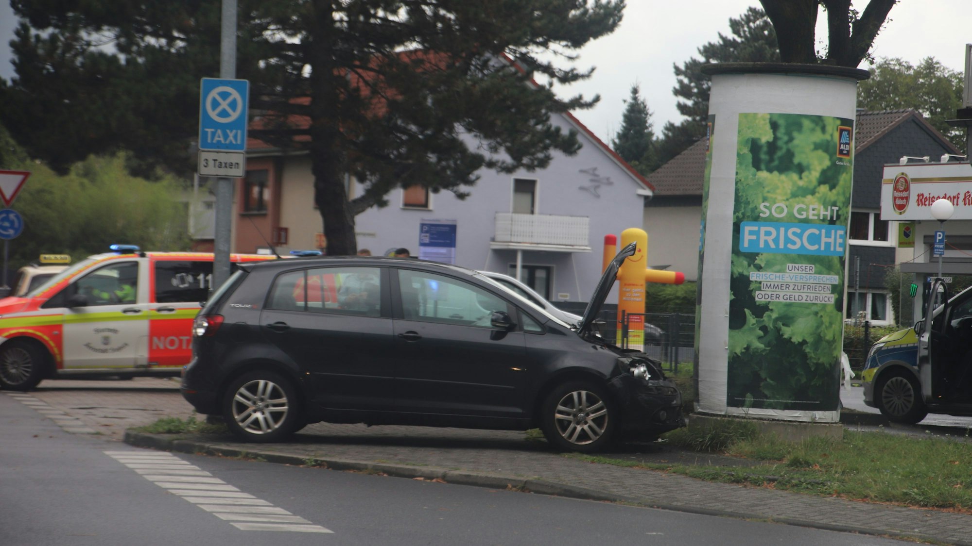 Ein Auto steht nach einem Zusammenstoß vor einer Werbesäule.