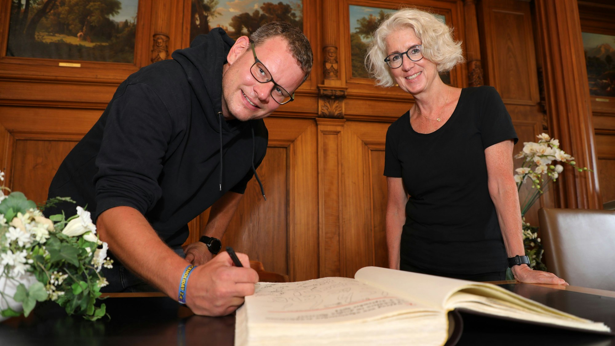 Die Lehrer Andreas Ruigk und Nicole Jakoby tragen sich ins Goldene Buch der Stadt Bergisch Gladbach ein.
