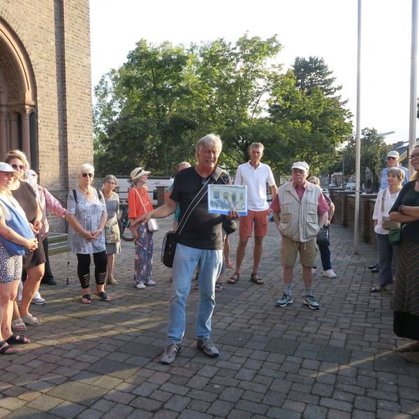 Zu sehen sind Besucher einer Führung vor dem Haupteingang von St. Rochus.