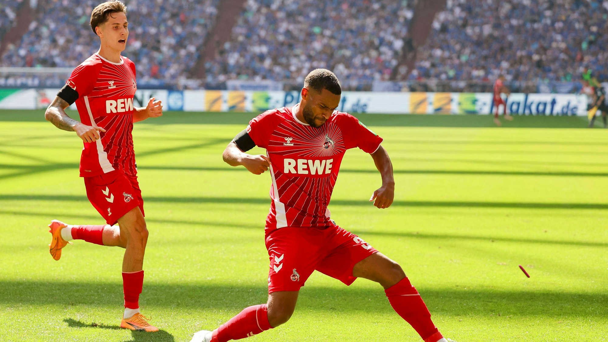 Linton Maina vom 1. FC Koeln bejubelt auf Schalke seinen Treffer zum 0:2 mit Denis Huseinbasic.