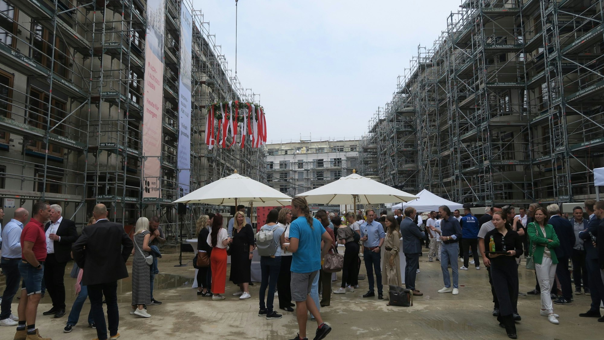 Zu sehen sind Richtfest-Besucher, die inmitten einer Wohnungsbaustelle stehen.