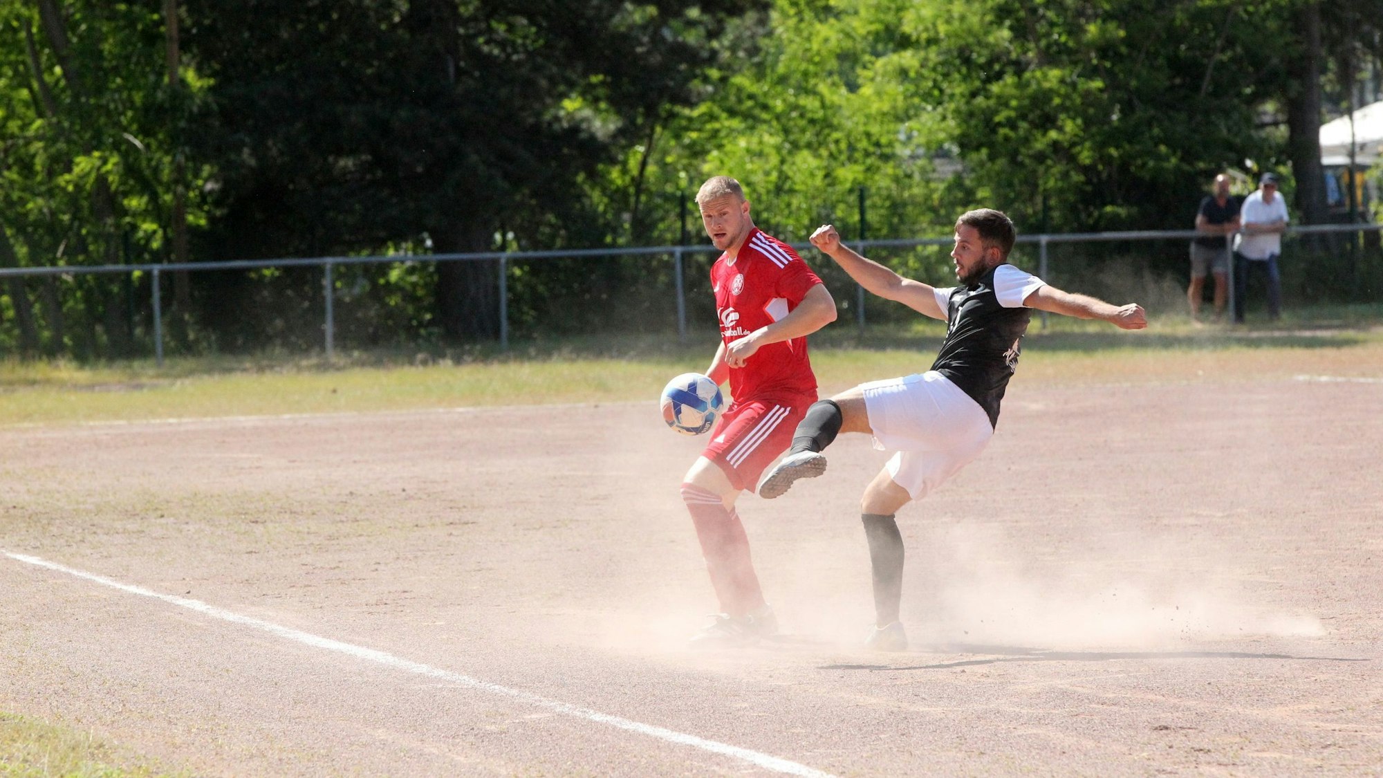 Zwei Spieler des TuS Zülpich und der TuS Mechernich treffen aufeinander. Der Aschenplatz staubt.