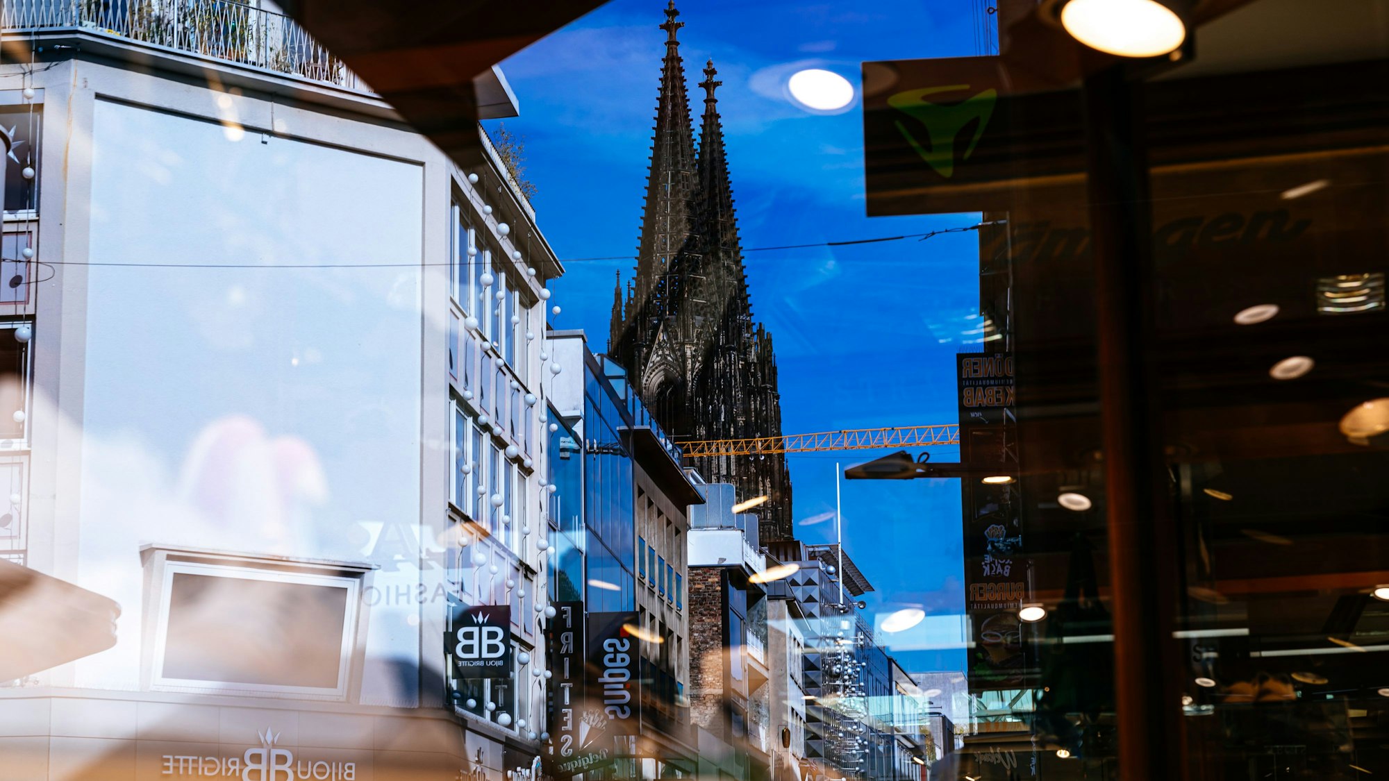 Der Kölner Dom spiegelt sich in Schaufensterscheiben.