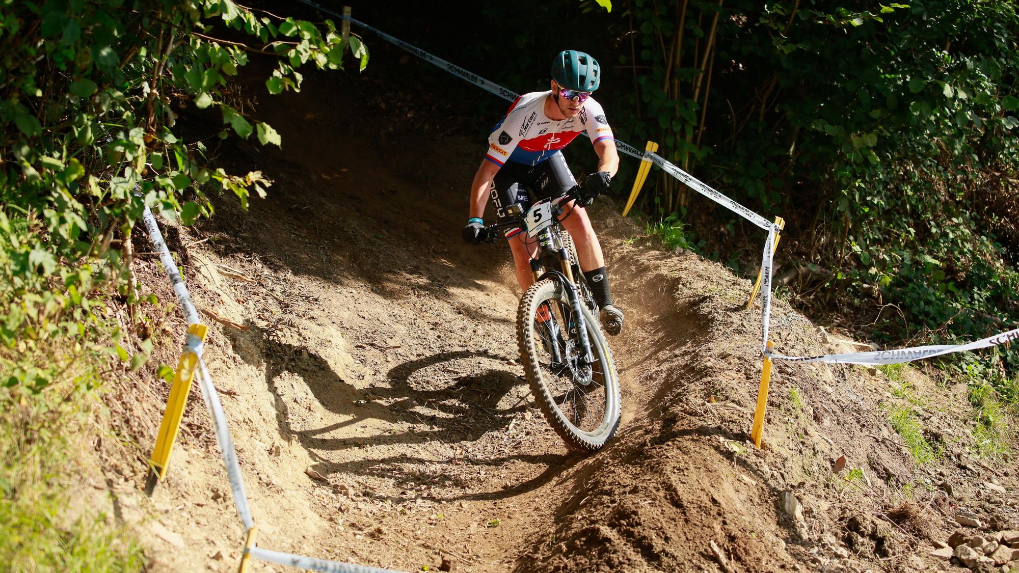 Ein E-Mountainbiker fährt bei einem Rennen über einen Waldkurs.