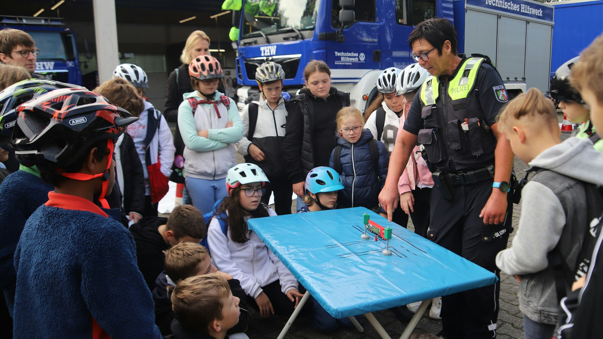 Eine Polizistin erklärt Kindern an einem Tisch eine Verkehrssituation.