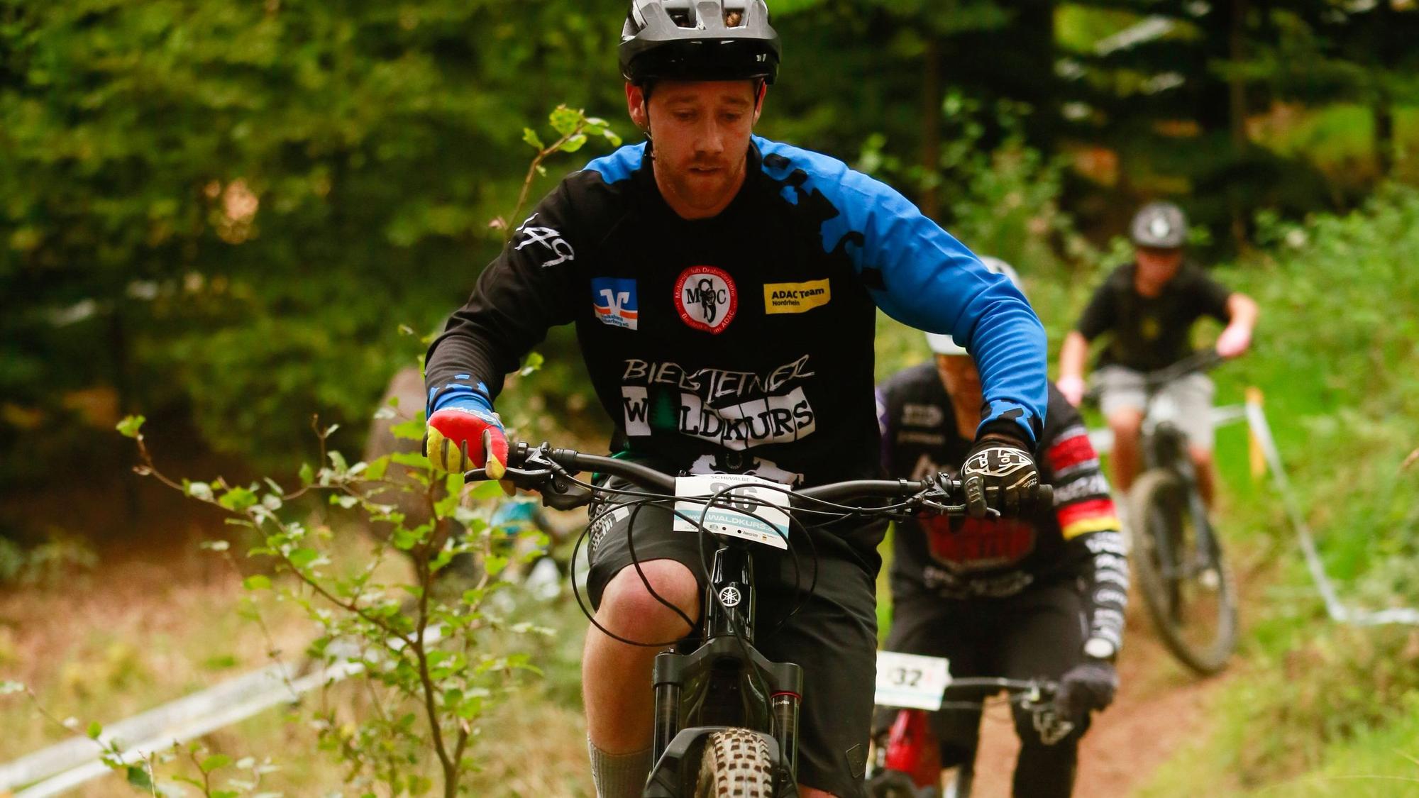 Ein E-Mountainbiker fährt bei einem Rennen über einen Waldkurs.