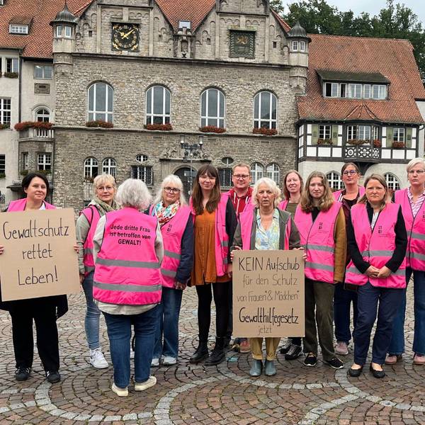 15 Teilnehmende stehen vor dem Rathaus und tragen pinke Westen.