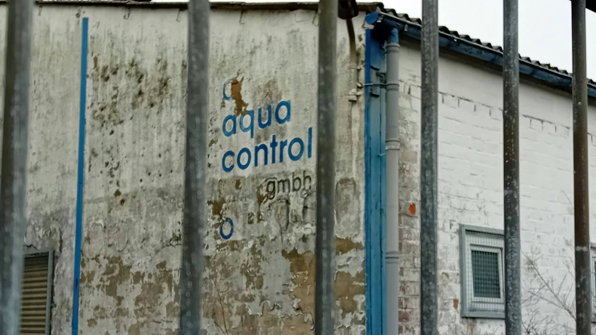 Der Schriftzug der Firma Aqua Control hinter einem Absperrgitter.