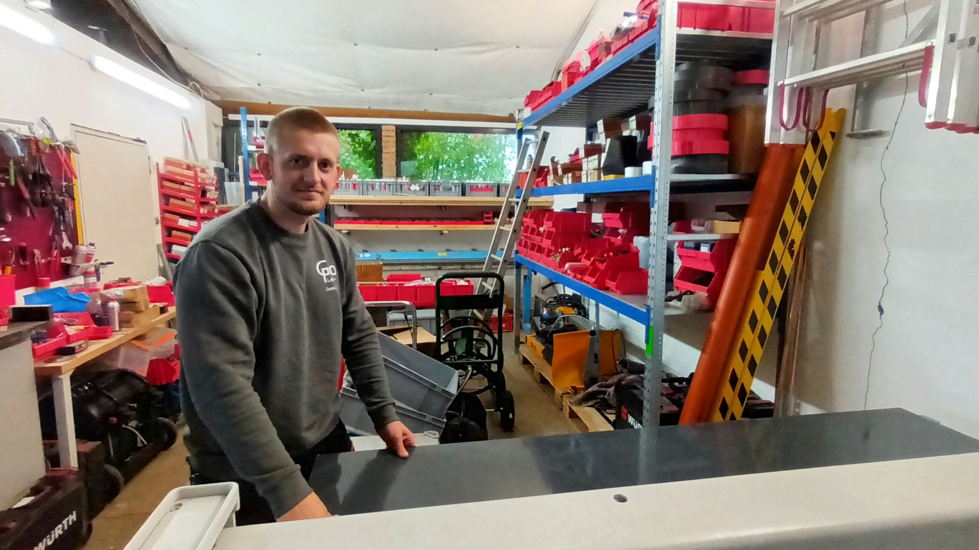 Ein Mann steht in einer Werkstatt an einer Schneidemaschine