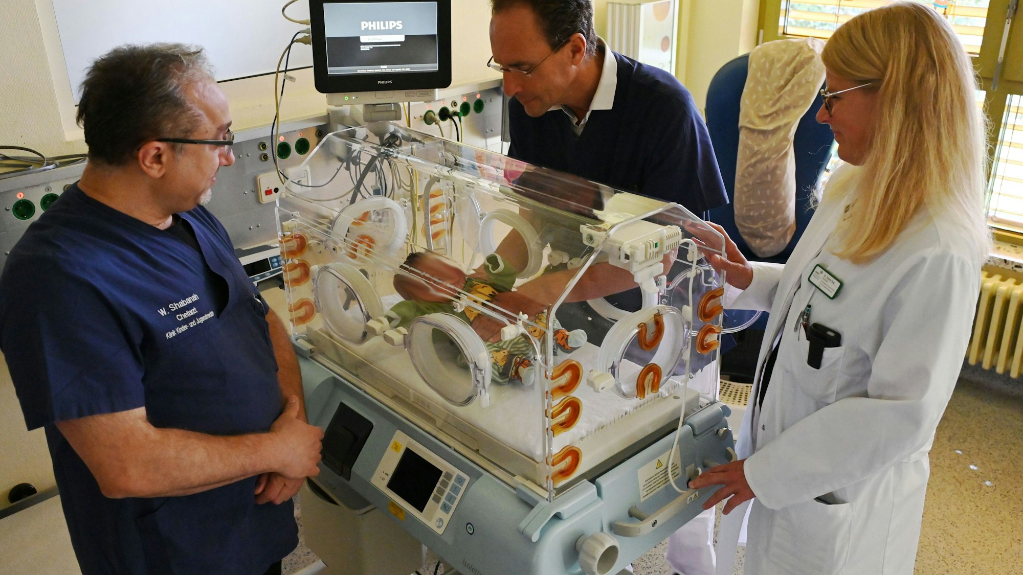 Wael Shabanah, Dr. Herbert Schade und Tatjana Klug kümmern sich um einen Säugling.