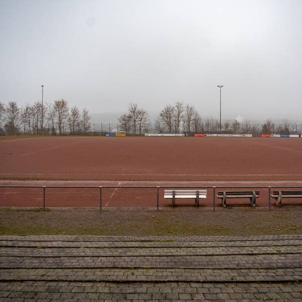Ein Blick von der Tribüne auf das Eifelstadion. Im Vordergrund stehen drei Bänke.