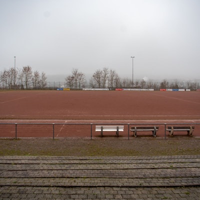Ein Blick von der Tribüne auf das Eifelstadion. Im Vordergrund stehen drei Bänke.