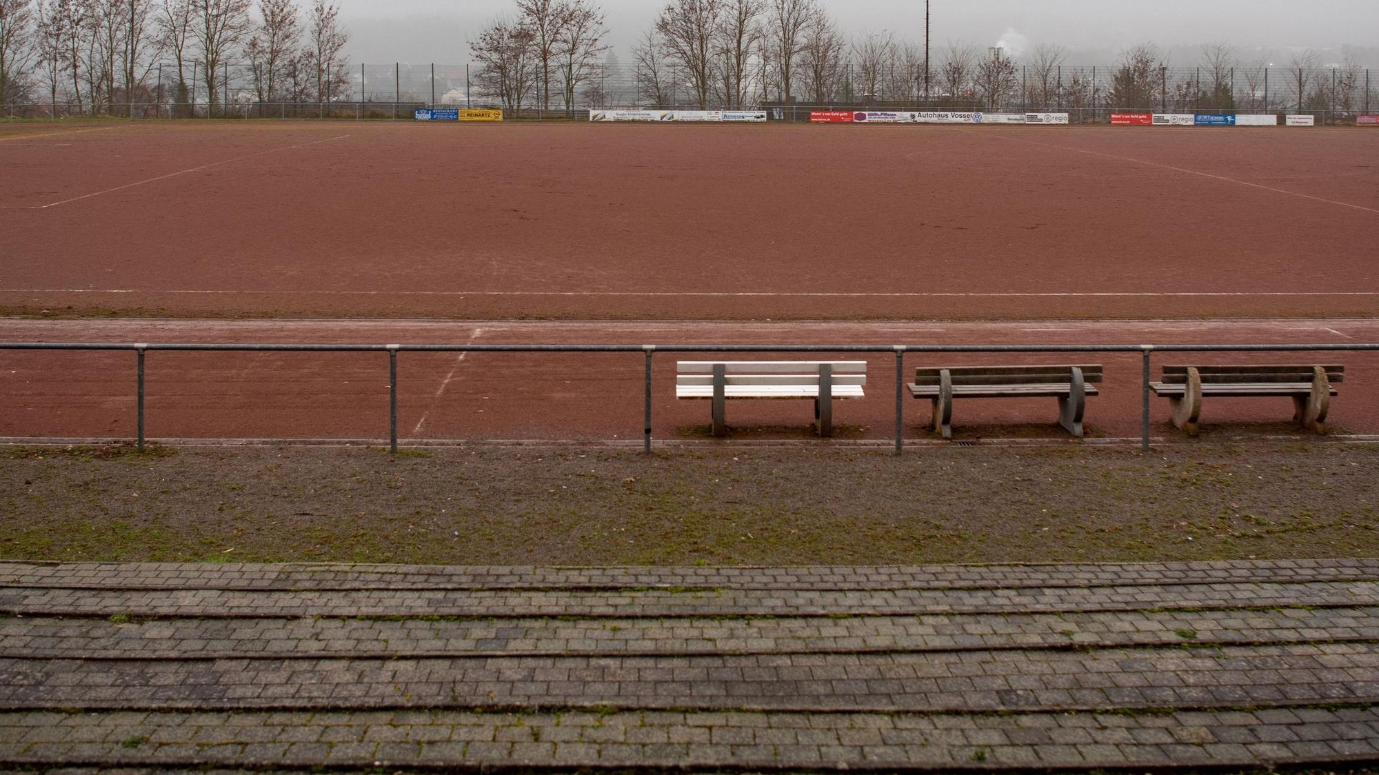 Ein Blick von der Tribüne auf das Eifelstadion. Im Vordergrund stehen drei Bänke.