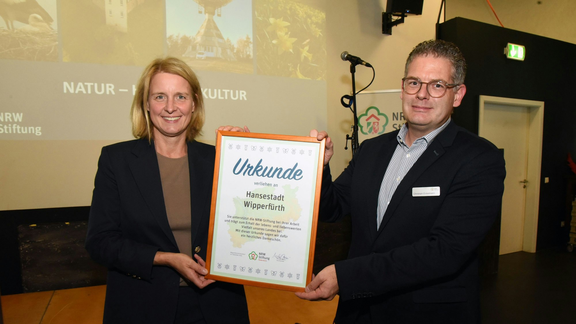 Ein Mann und eine Frau halten eine große Urkunde in Händen.