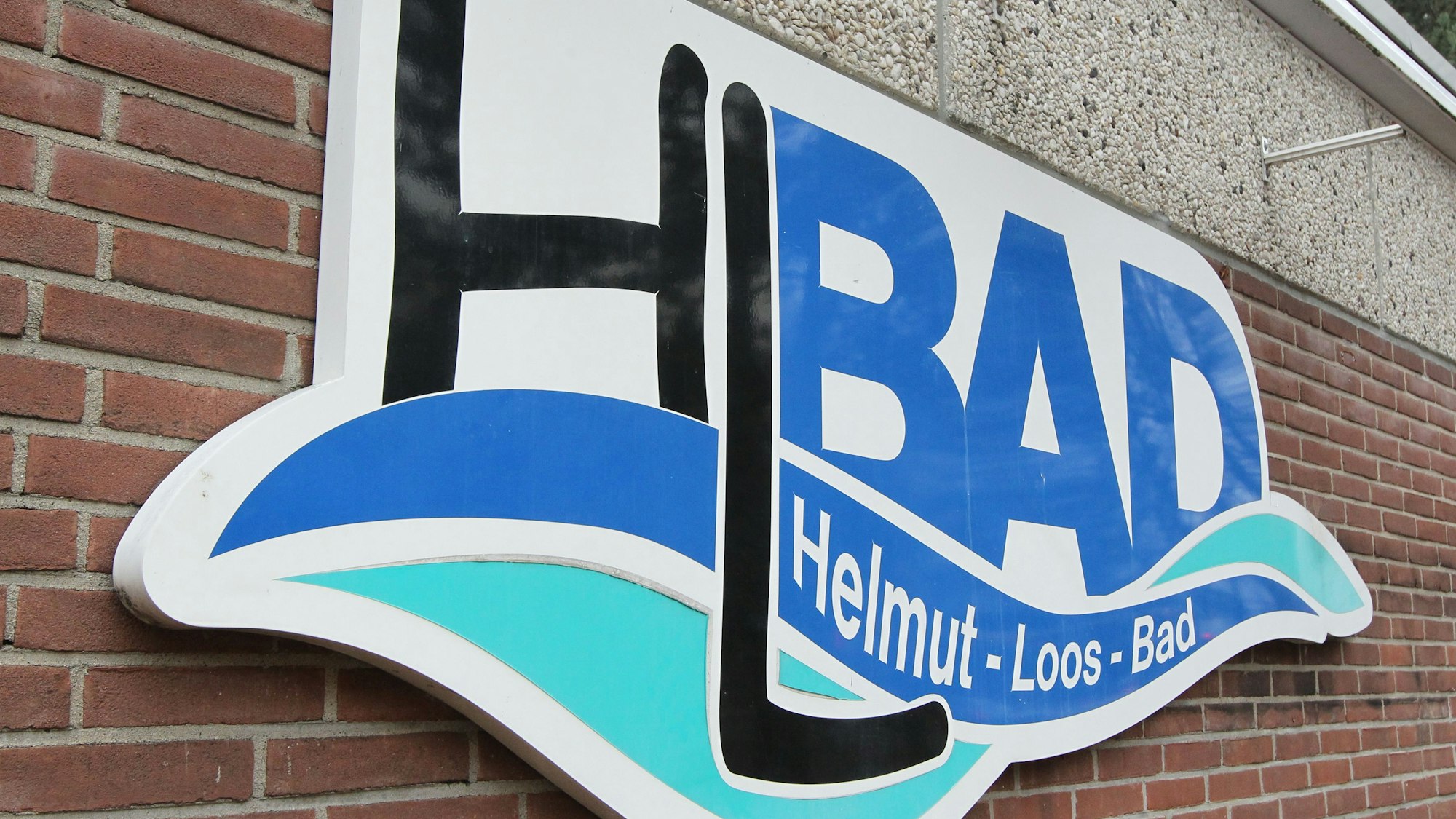 Das Logo des Hallenbades in Niederkassel-Lülsdorf an einer Backsteinmauer.