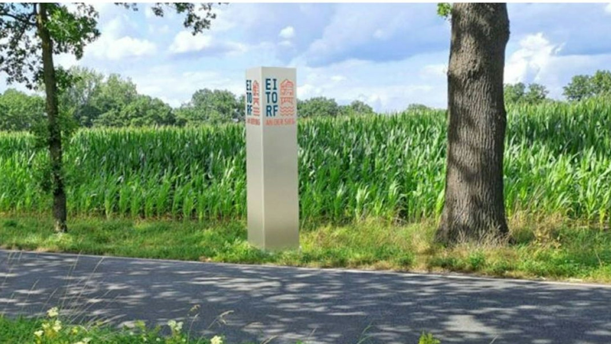 Visualisierung einer eckigen, silberfarbenen Stele mit Eitorf-Logo in Blau und Rot an einer Straße.