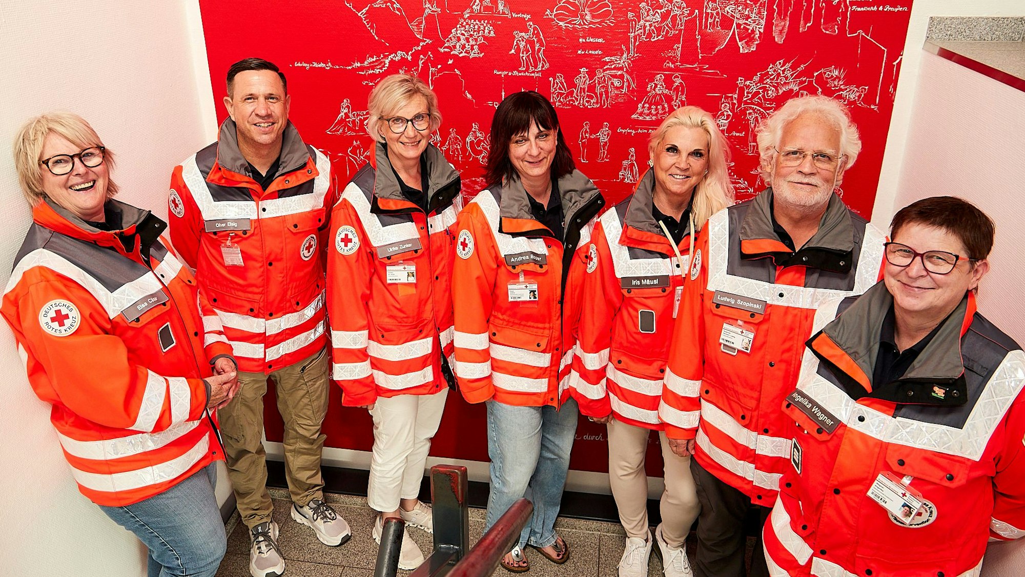 Einige Mitglieder des Kriseninterventionsteams im Kreis Euskirchen stehen im Haus des DRK-Kreisverbands vor einem rot-weißen Kunstwerk.