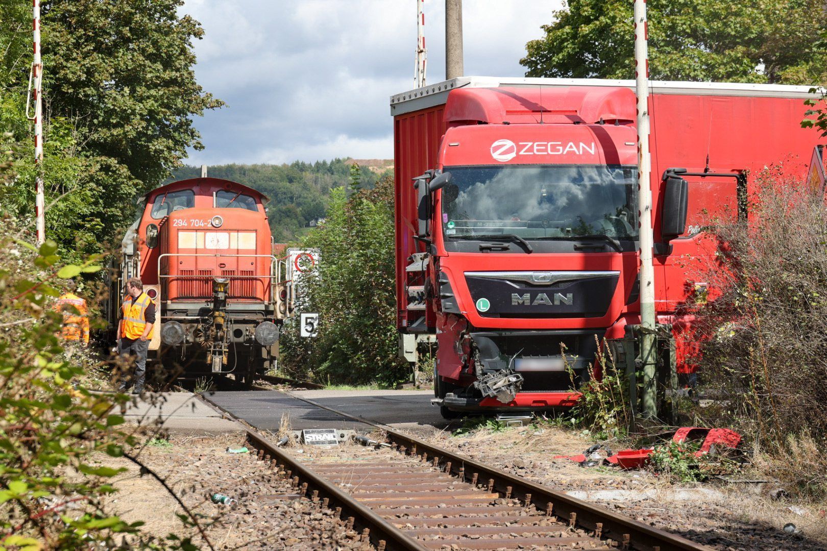 Rettungskräfte sind am Bahnübergang nach einem Unfall zwischen einem unbeladenem Güterzug und einem Sattelschlepper im Einsatz. Beim Aufprall eines Lastwagens auf einen Güterzug im saarländischen Schmelz (Landkreis Saarlouis) ist der Lkw-Fahrer verletzt worden.