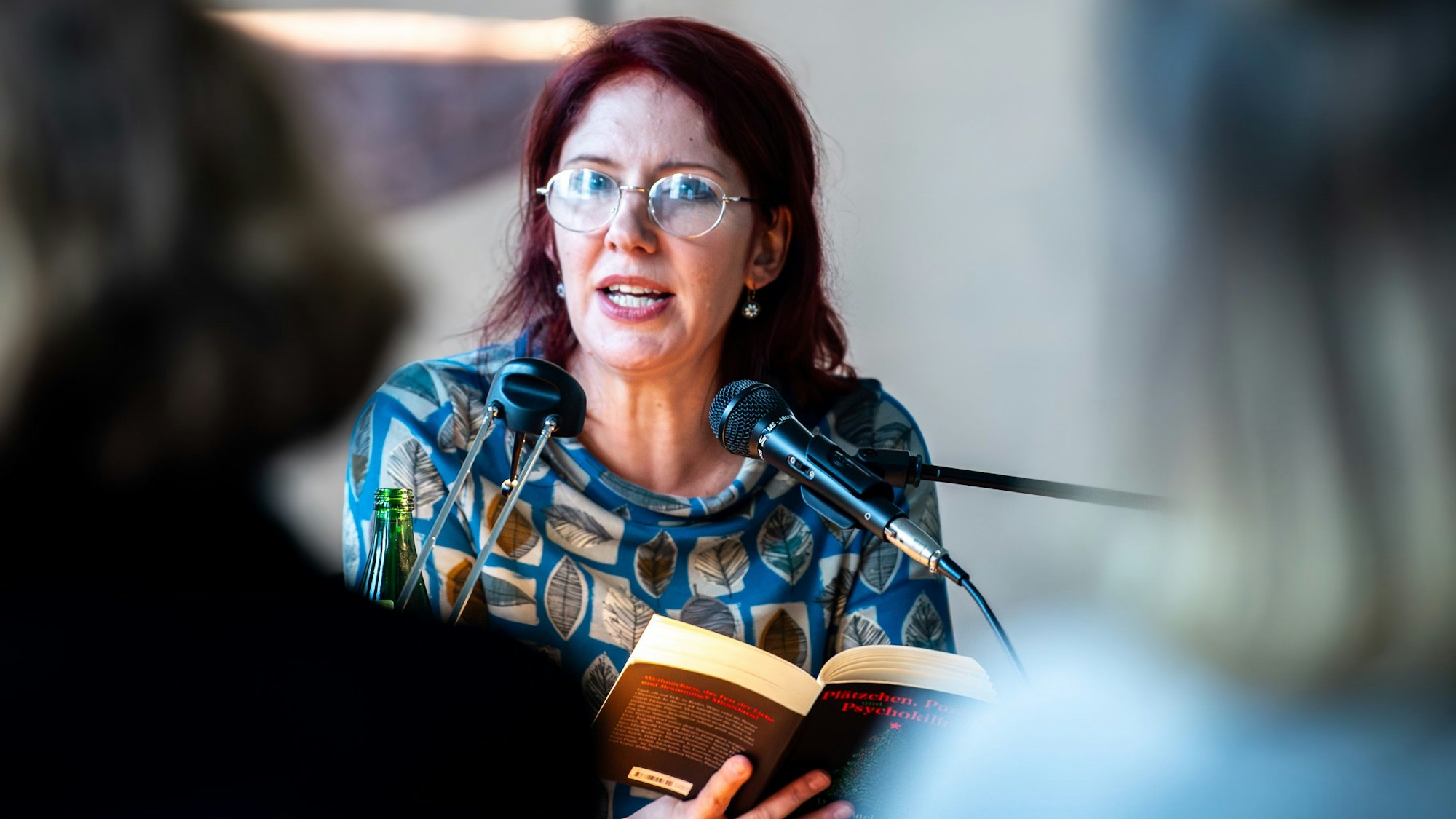 Das Bild zeigt Judith Merchant während der Lesung. Sie hat ein Buch in den Händen.