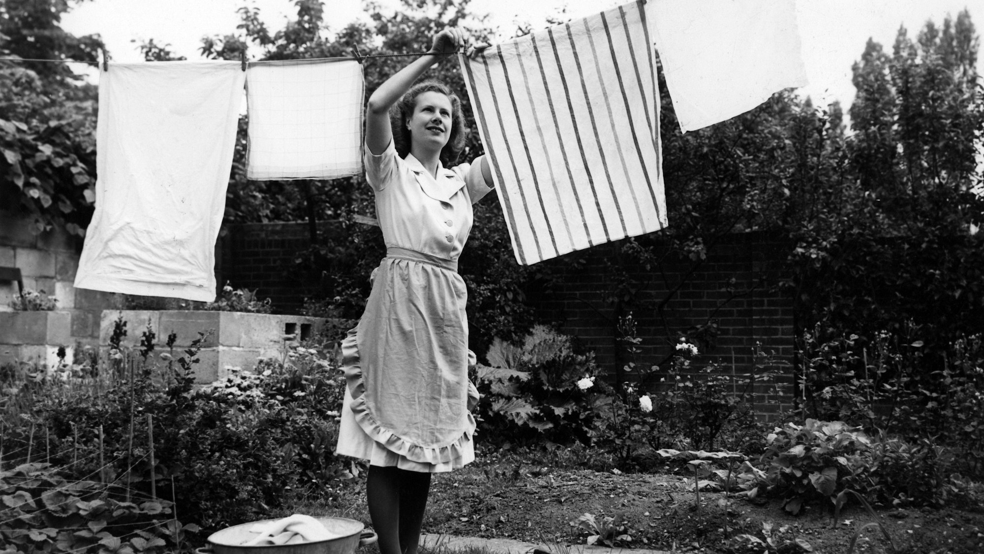 Schwarz-weiß-Foto einer Frau aus dem Jahr 1959, die Wäsche aufhängt.