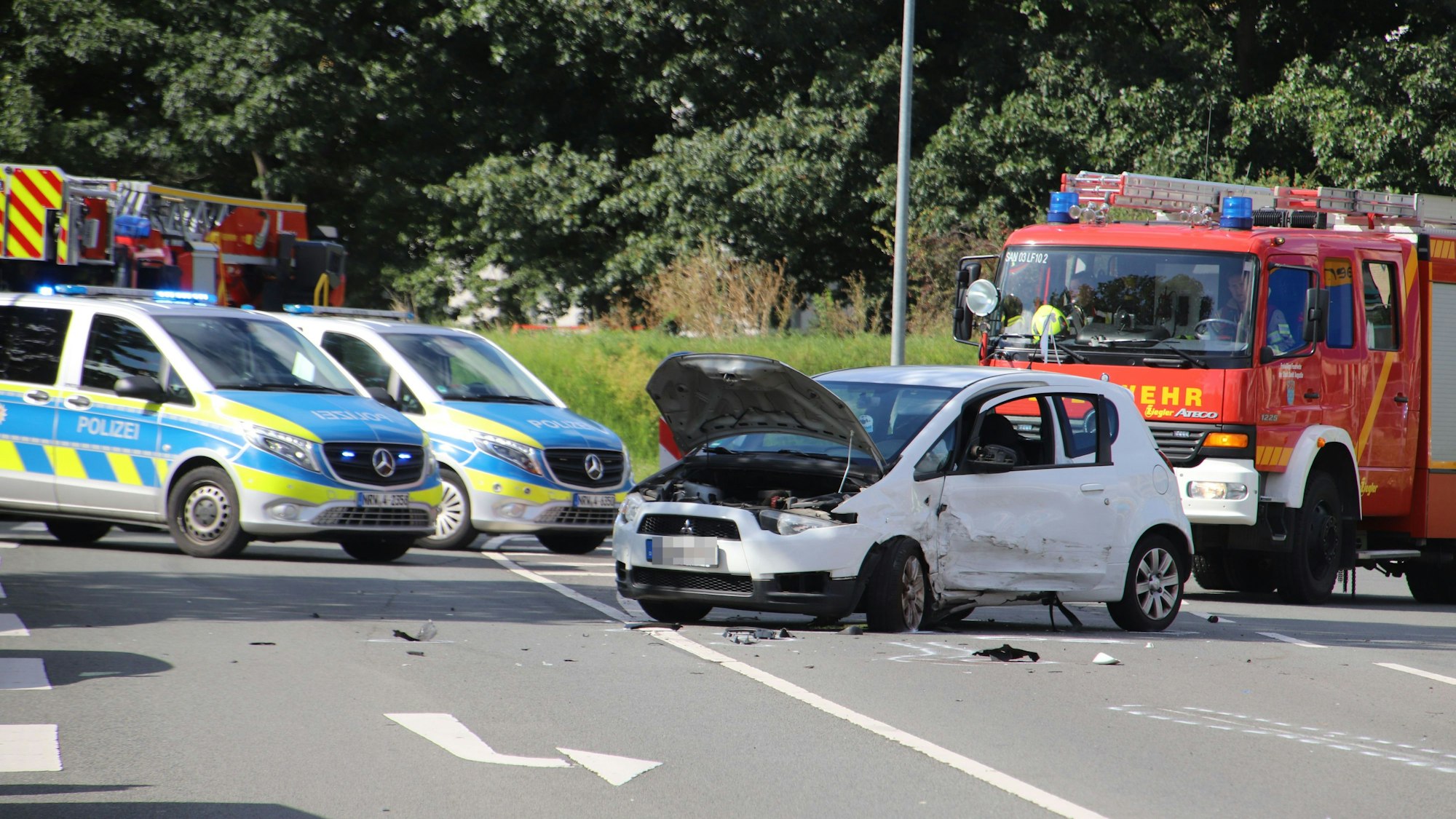 Ein schwer beschädigtes Auto steht vor Polizei- und Feuerwehrfahrzeugen.
