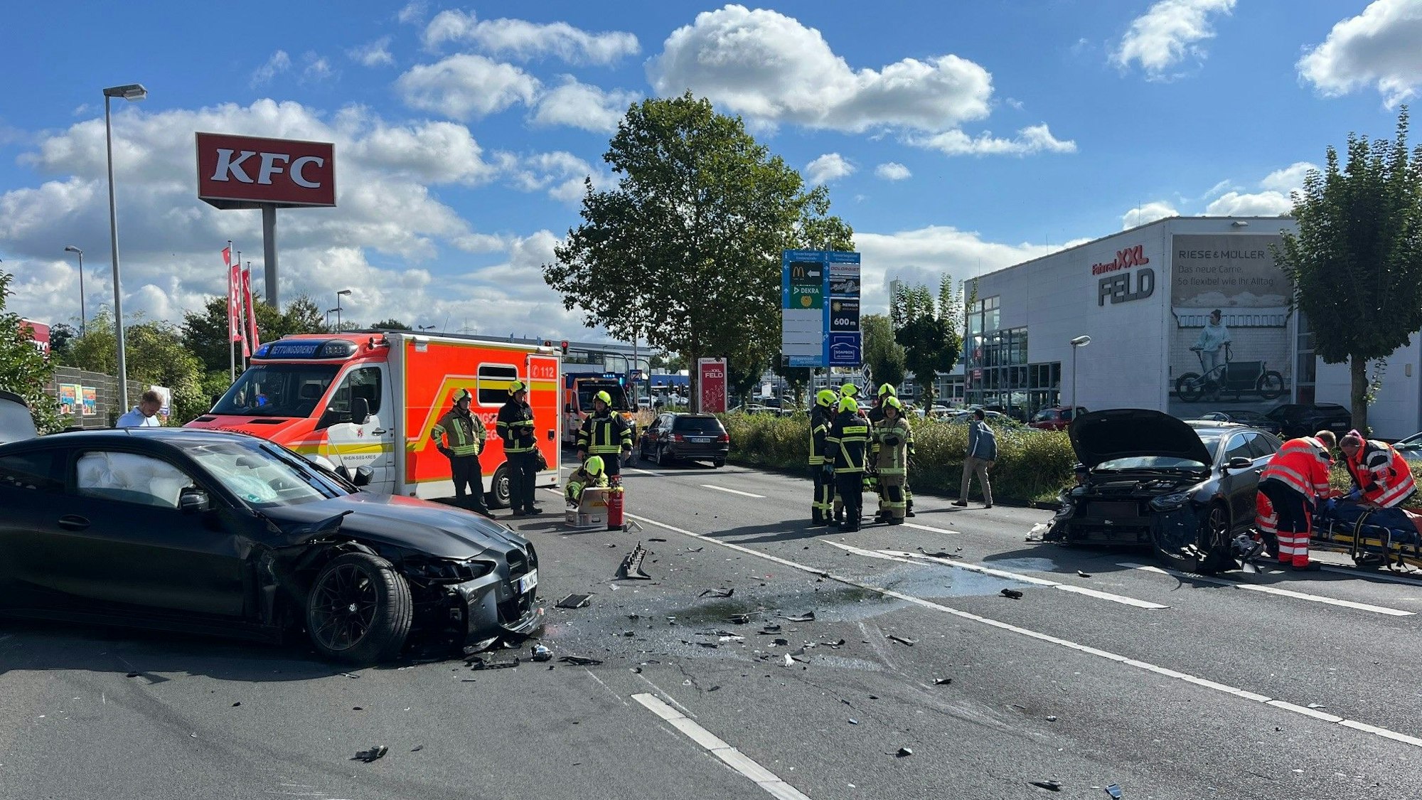 Rettungskräfte stehen zwischen zwei zerstörten Autos auf einer Straße.