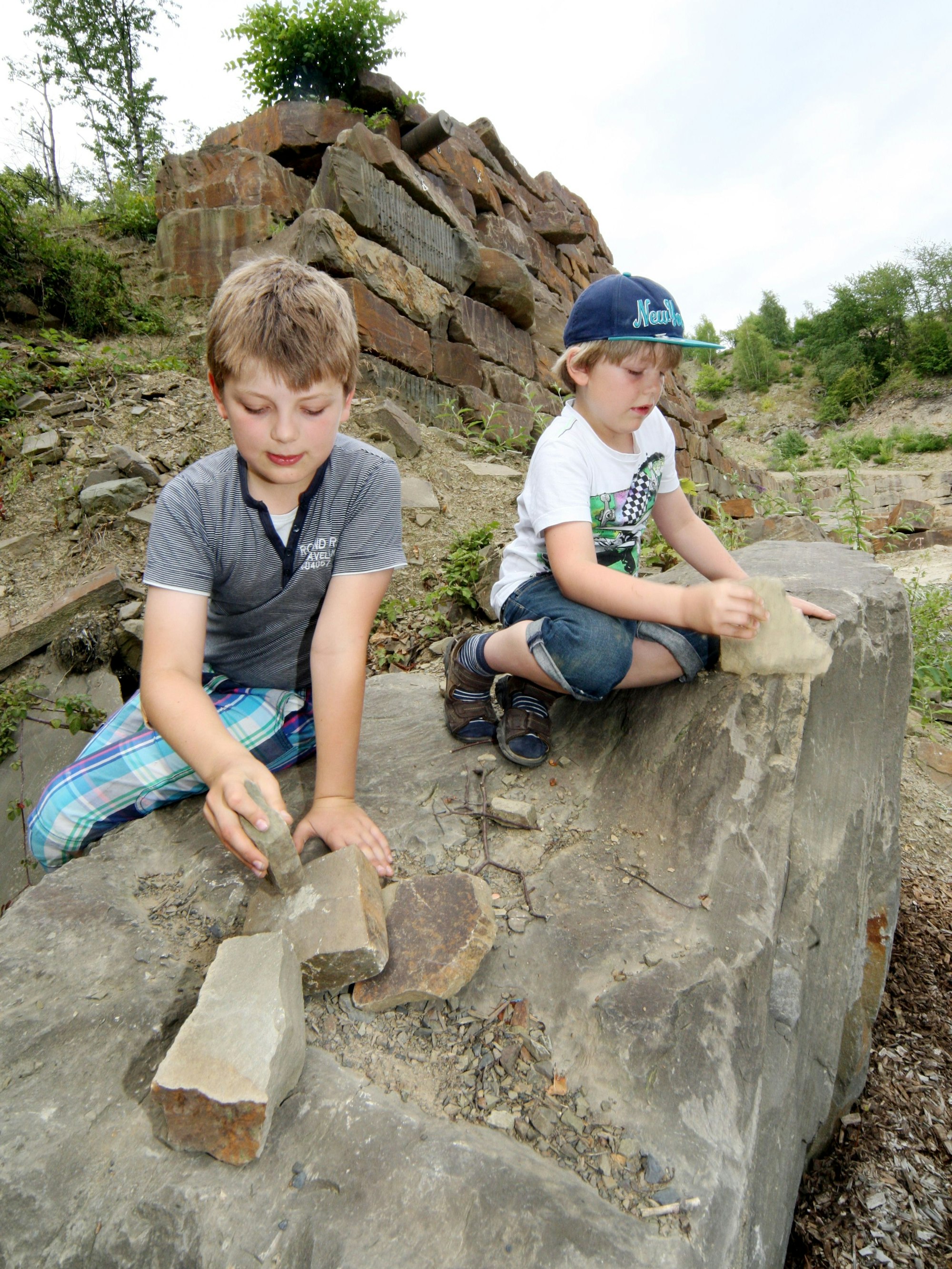 Zwei Kinder klopfen Steine am Steinhauerpfad in Lindlar.