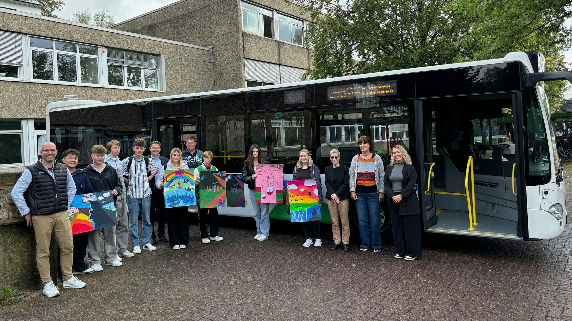 Eine Schülergruppe steht mit Bildern gegen Komasaufen in den Händen vor einem Linienbus.