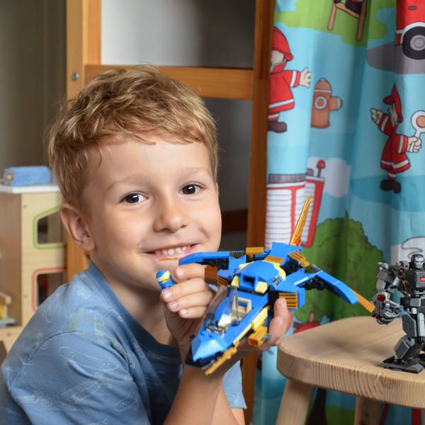 Ein Junge zeigt ein von ihm gebasteltes Lego-Spielzeug.