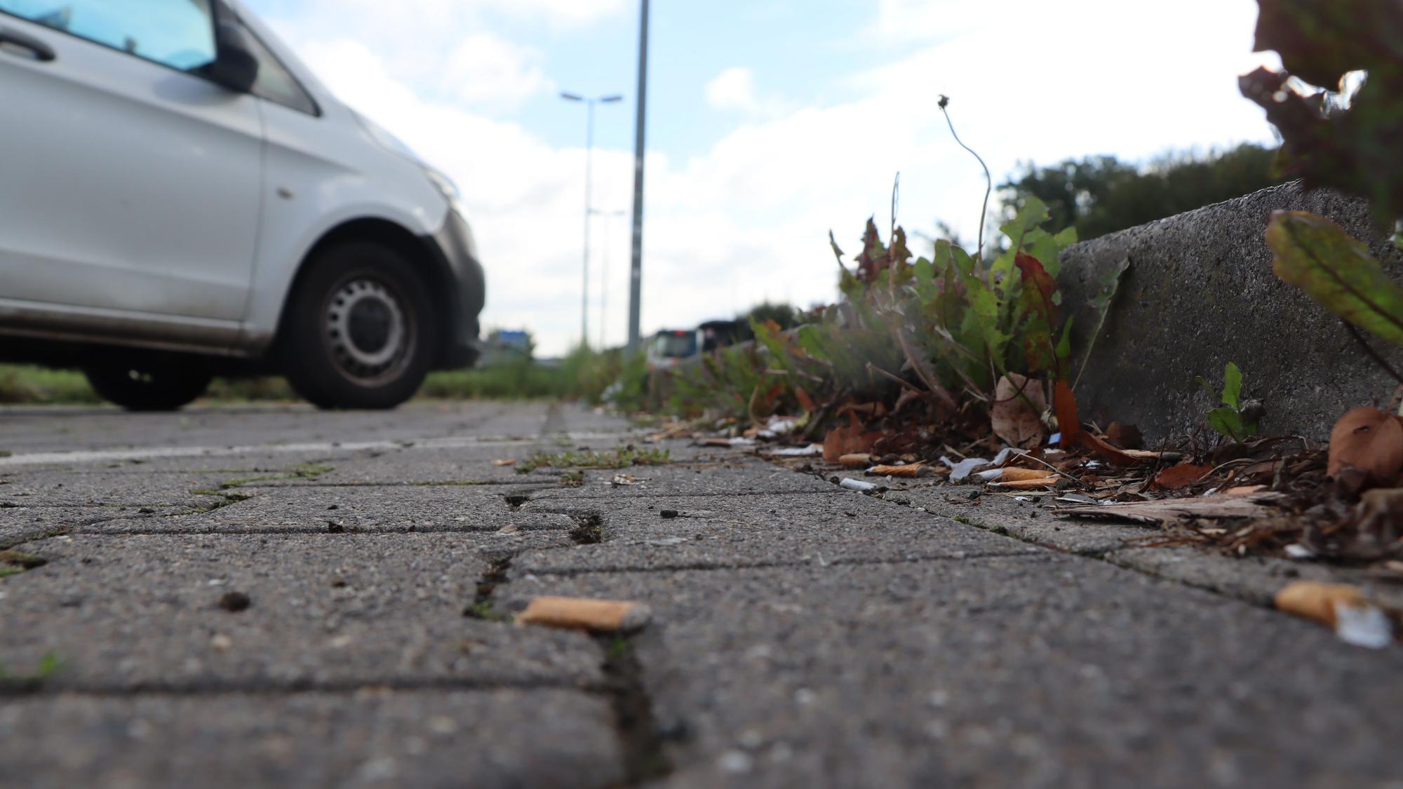 Auf dem Boden des Parkplatzes liegen weggeworfene Zigaretten.