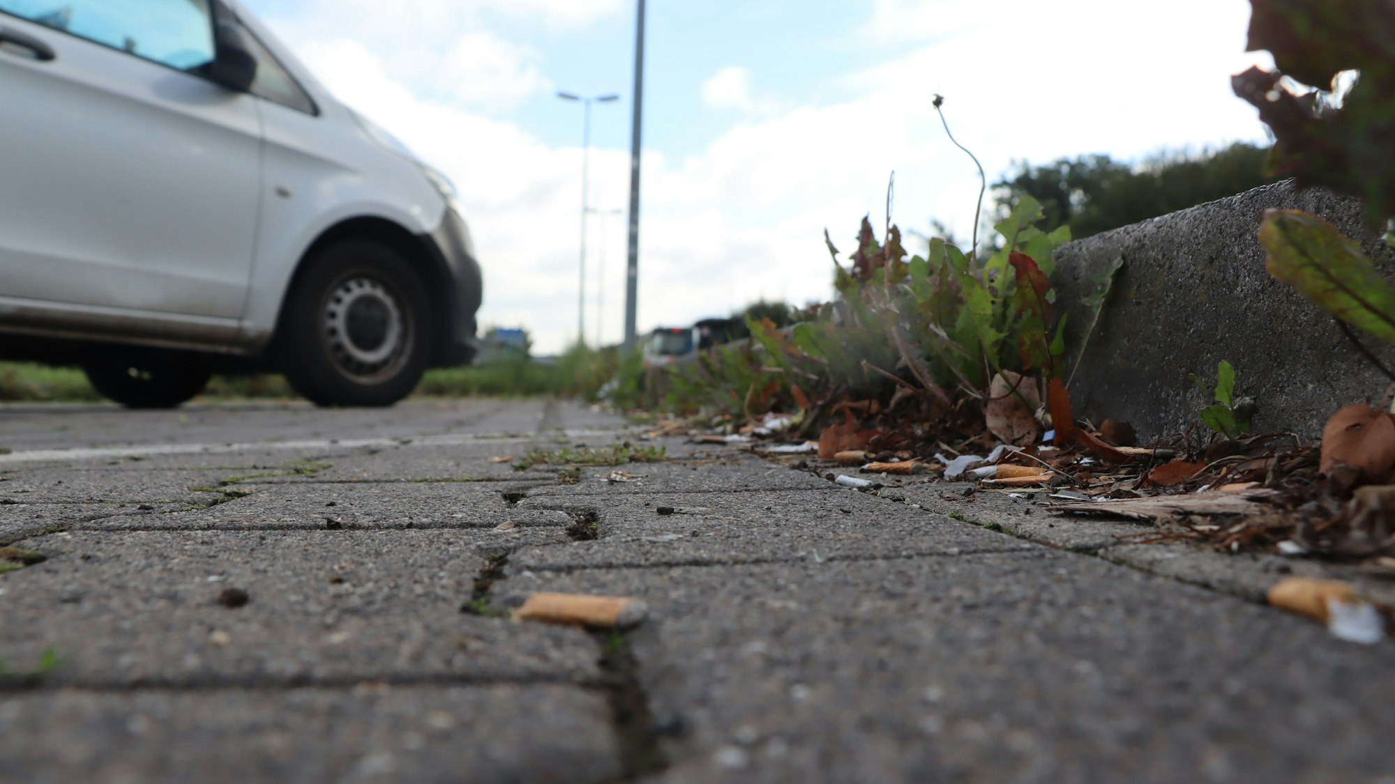 Auf dem Boden des Parkplatzes liegen weggeworfene Zigaretten.