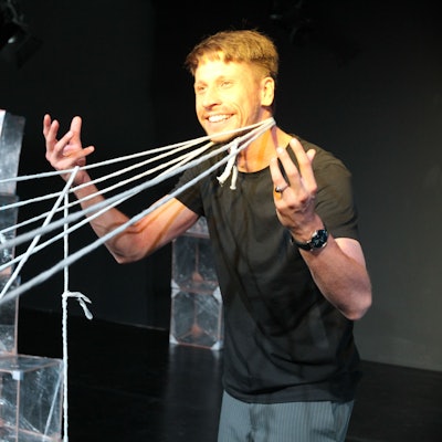 Ein Mann hält gespannte Wollfäden an den Händen