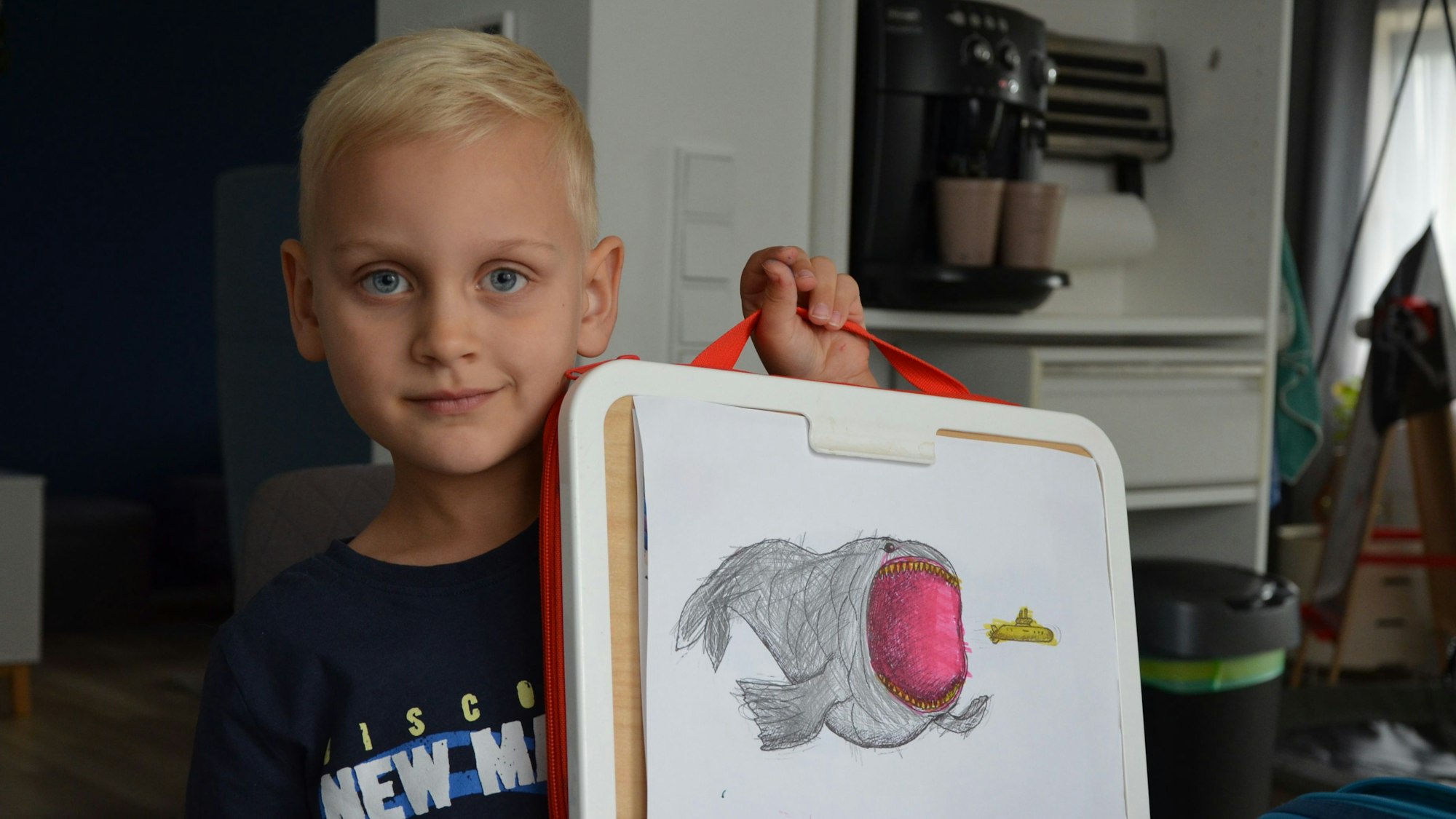 Ein Junge zeigt ein von ihm gemaltes Seemonster.